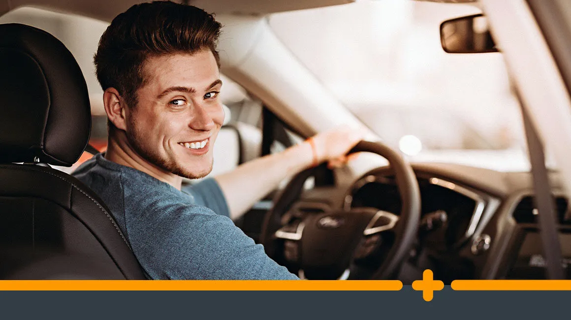 Młody mężczyzna w samochodzie, gotowy do jazdy, spoglądający przez ramię